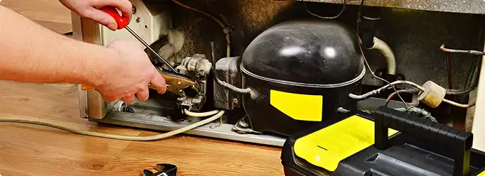 Refrigerator repair technician fixing the compressor and wiring in Channelview, TX