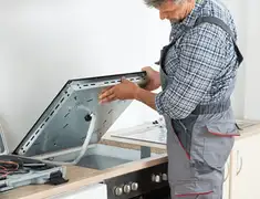 Appliance repair technician installing a built-in cooktop in Houston, TX