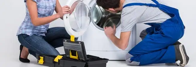 Washer repair technician inspecting a front-load washing machine with tools in Houston, TX