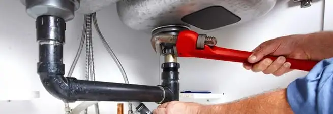 Garbage disposal repair technician tightening the sink drain and disposal connection in Houston, TX