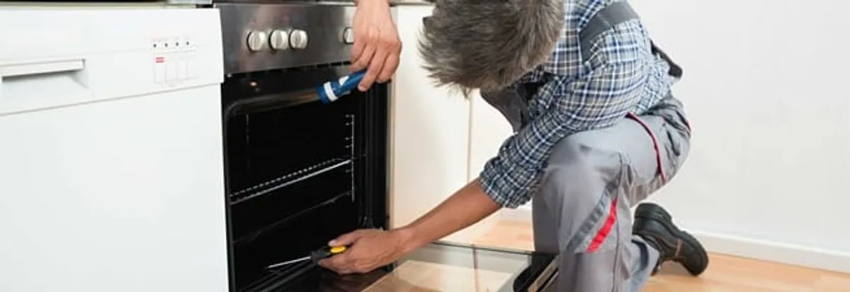 Oven repair technician inspecting and servicing an electric oven in Houston, TX