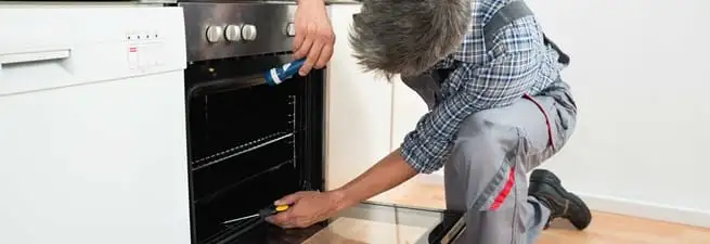 Oven repair technician inspecting and servicing an electric oven in Houston, TX