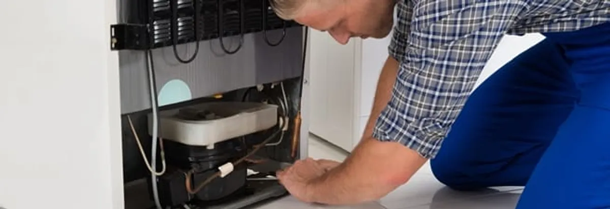 Refrigerator repair technician servicing the compressor and condenser area in Houston, TX