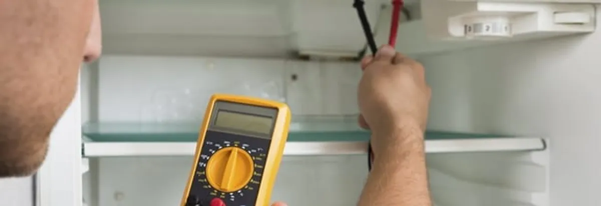 Refrigerator repair technician testing electrical components with a multimeter in Houston, TX