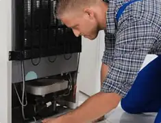 Refrigerator repair technician servicing the compressor and condenser area in Houston, TX