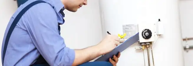 Water heater repair technician inspecting the unit and recording service notes in Houston, TX