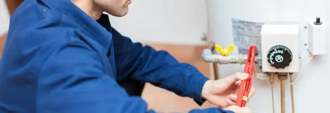 Water heater repair technician adjusting the temperature control and gas valve in Houston, TX
